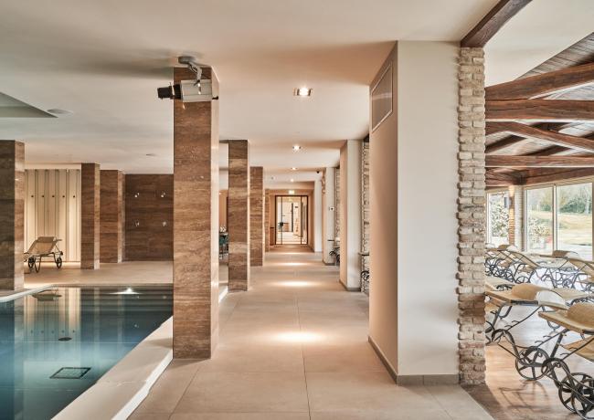 Indoor pool with loungers, columns, and large windows.