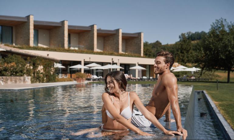 Coppia sorridente in piscina di un resort moderno.