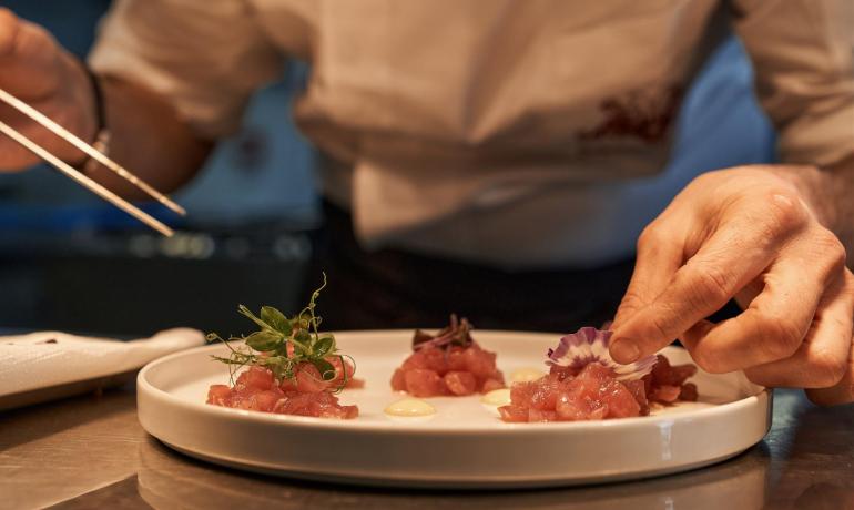 Chef prepara un piatto gourmet con cura e precisione.